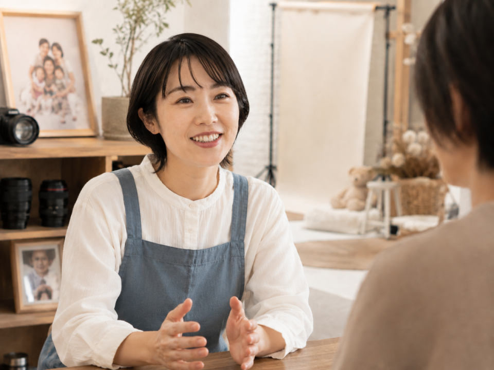 写真スタジオでお客様に撮影プランや料金を説明するオーナーのイメージ